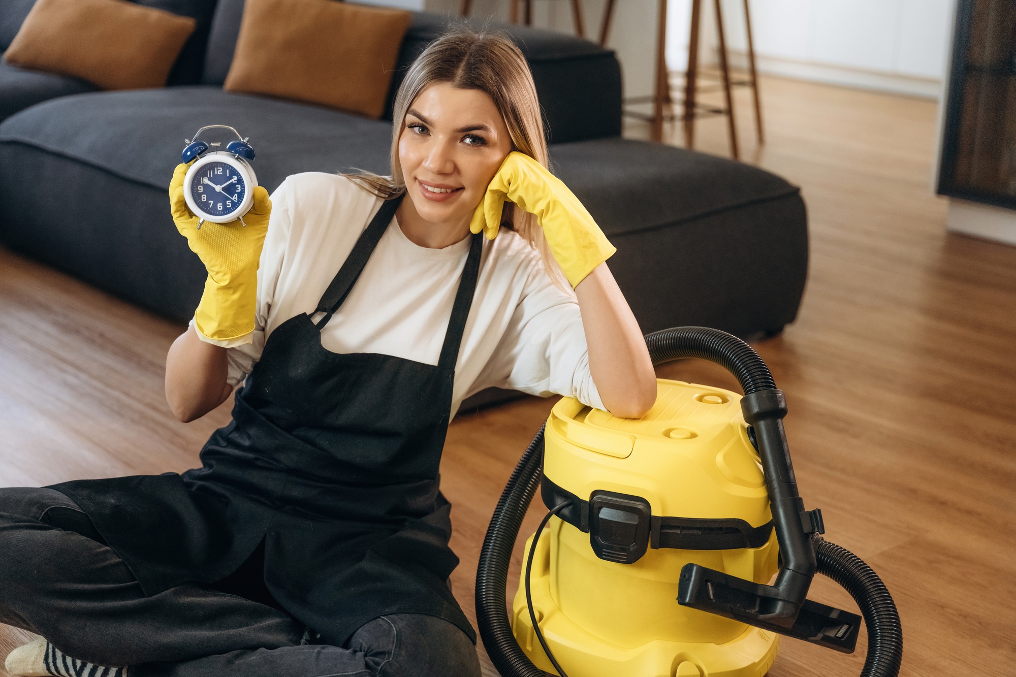 Time is running out, with clock. Female professional cleaning service worker is domestic room